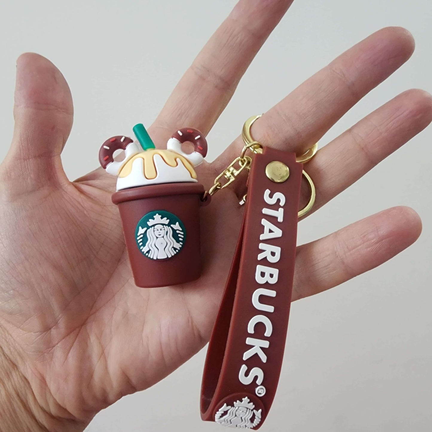 Cute Starbucks key ring featuring a mini frappuccino charm with a brown strap, perfect for coffee lovers.