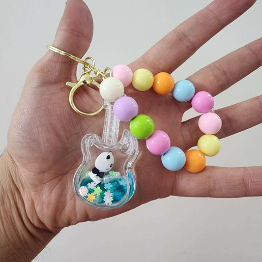 Colorful key ring with a guitar shape and bead accents, held in a hand, ideal for key organization.