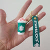Hand holding a Starbucks key ring featuring a mini frappuccino charm with whipped cream.